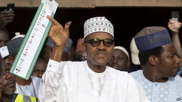 Opposition candidate Gen Muhammadu Buhari holds his ballot paper in the air before casting his vote in his home town of Daura, northern Nigeria 28 March 2015