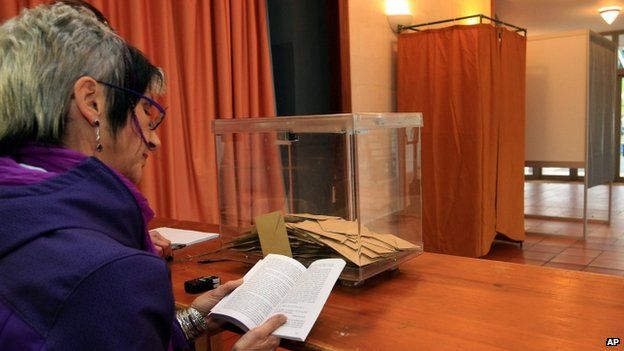 Marie Buck, an councillor, reads a book at a polling station during the first round of local elections, 22 March 2015,