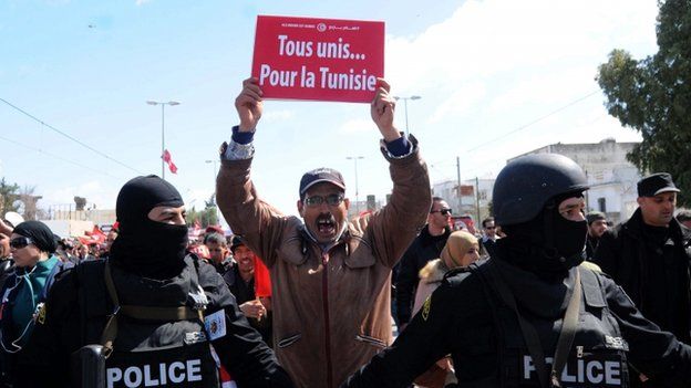 Tunisian soldiers guard as a protester holds a placard reading "all united for Tunisia" during a march to denounce terrorism, in Tunis, Tunisia, 29 March 2015