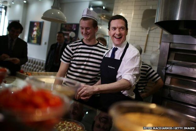 Conservative Chancellor George Osborne (right) prepares a pizza with the help of staff member Will Jessell during a visit to a Pizza Express restaurant in Hove, England.