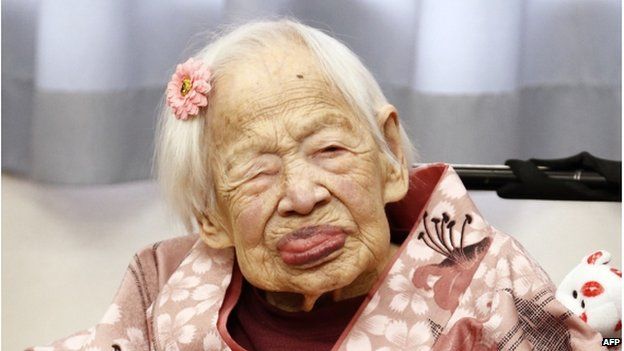 This picture taken on 4 March 2015 shows the world's oldest woman Misao Okawa (C) posing for a photo at her nursing home in Osaka, western Japan