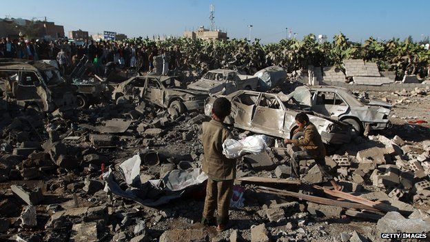 Yemenis stand at the site of a Saudi air strike against Huthi rebels near Sanaa Airport on March 26, 2015