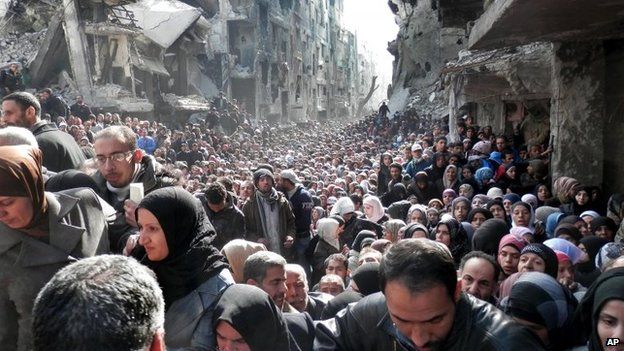File photo: Residents of the besieged Palestinian camp of Yarmouk queue to receive food supplies in Damascus, Syria, 31 January 2014