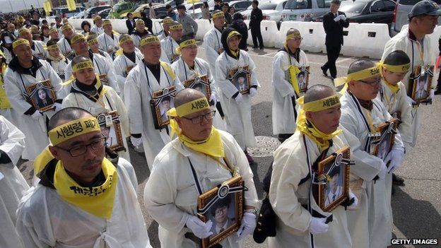 Grieving parents of victims of the Sewol ferry disaster, wearing white mourning robes with shaved heads