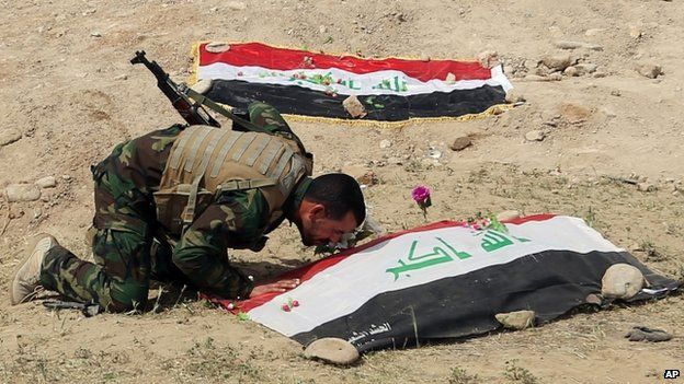 A Shia militiaman kisses the grave at a site believed to be a mass grave where Islamic State militants killed hundreds of Iraqi soldiers when they overran Camp Speicher military base last June, in Tikrit, Iraq, on 3 April 2015