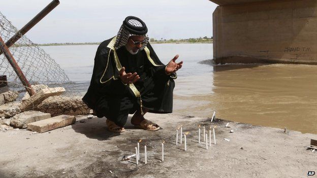 An Iraqi man prays for his slain relative at the platform on the Tigris River where Islamic State extremists are believed to have killed hundreds of Iraqi soldiers when they overran Camp Speicher military base last June, in Tikrit, Iraq, 3 April 2015