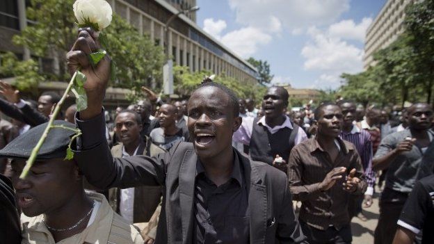 A Kenyan student, wearing black to represent mourning, holds a white rose as he marches with others in memory of the victims of the Garissa college attack and to protest what they say is a lack of security, in downtown Nairobi, Kenya Tuesday, April 7, 2015.
