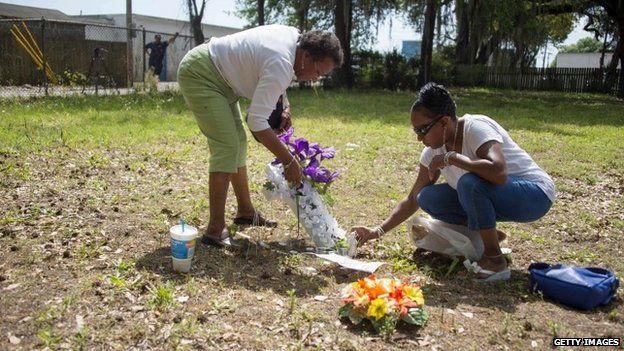 Barbara Scott (R), cousin of Walter Scott, the 50-year-old man who was killed after being fired at eight times as he ran away from an officer after a traffic stop, lays flowers with her mother Evaliana Smalls (L) at the lot where the incident happened in North Charleston, South Carolina on 8 April 2015