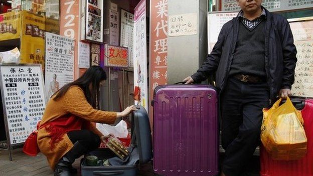 Mainland Chinese shoppers pack goods into suitcases in Hong Kong (9 Feb 2015)