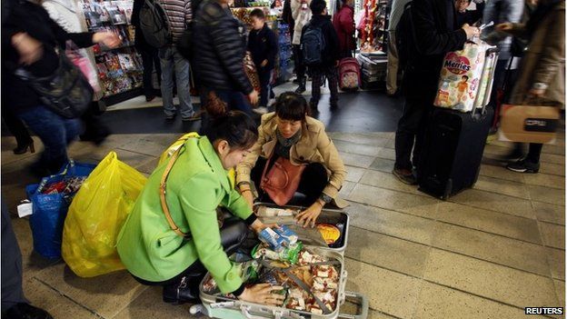 Mainland Chinese shoppers pack goods into suitcases in Hong Kong (9 Feb 2015)