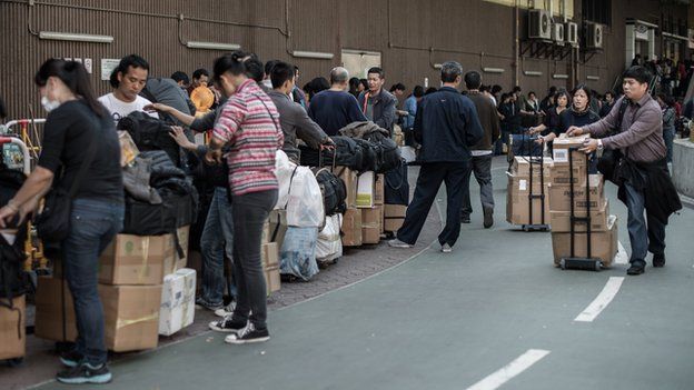 In this picture taken in Hong Kong on January 29, 2013, people arrive to queue up to get their packages weighed at the Sheung Shui train station prior to their journey back to mainland China.