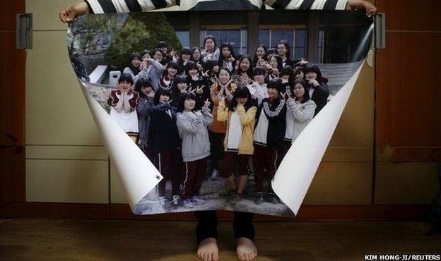 Eom Ji-yeong, mother of Park Ye-ji who died in the Sewol ferry disaster, poses for a photograph with a picture showing her daughter (44th from left in top row) with her schoolmates when she was 15