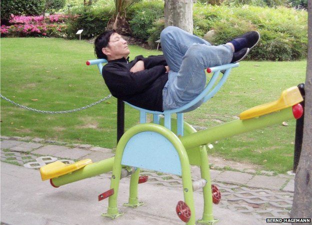 A man asleep on a child's see saw in China