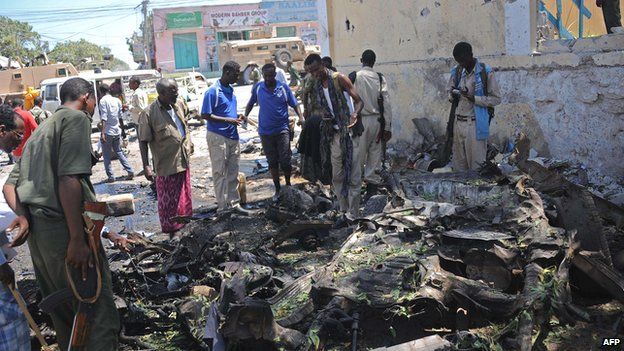 People look at the wreckage of a car bomb outside the higher education ministry in Mogadishu, Somalia on Tuesday