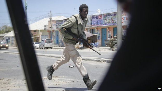 A Somali soldier runs during fighting following a car bomb that was detonated at the gates of a government office complex in Somalia's capital Mogadishu on Tuesday