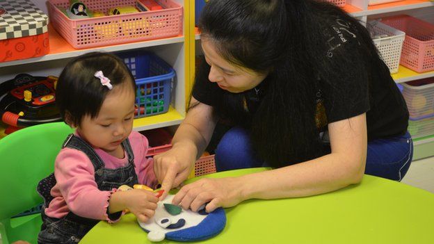 Yoyo Chan, left, sticks a felt mouth onto a felt face, under the supervision of tutor Teresa Fahy, 5 March 2015