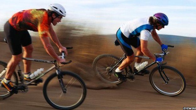 Two cyclists race along a dirt track