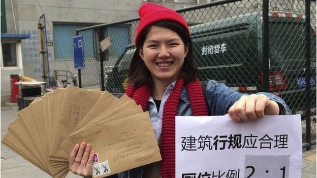 Women activist Li Tingting, 25, poses with letters and a paper which read "Construction regulations should be reasonable, bathroom proportion 2:1 (women/men)" in this undated file handout picture taken in an unknown location in China, provided by a women"s rights group on 8 April 2015
