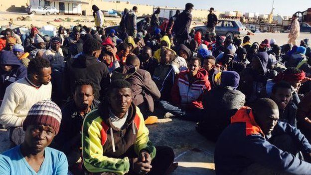 Migrants sit on the ground in Misrata