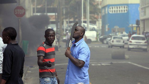 A foreigner holds a machete to protect himself after clashes broke out between a group of locals and police in Durban