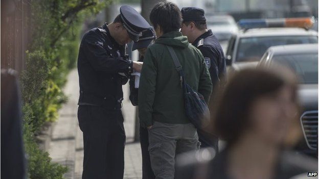 Police delete files in a Japanese journalist's camera outside the court in Beijing (17 April 2015)