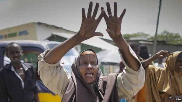 Woman cheers as she looks at demonstrators chanting "al-Shabab nichi" (Down with al-Shabab) in Garissa