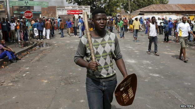A local gestures as he holds a stick and a shield outside a hostel during anti-immigrant related violence in Johannesburg, April 17, 2015