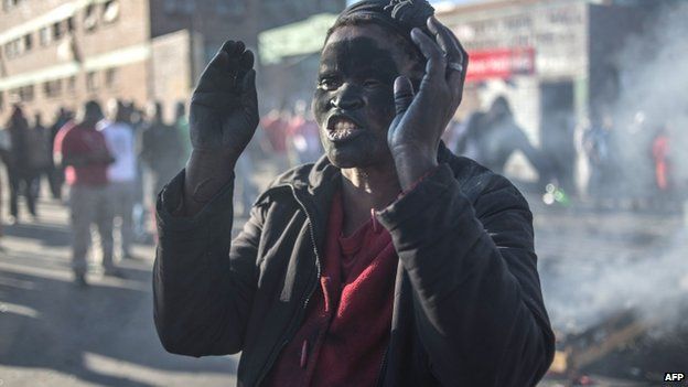 A women covered in soot gestures and shouts towards foreign nationals outside the Jeppies Hostles, in the Jeppestown area of Johannesburg, on April 17, 2015