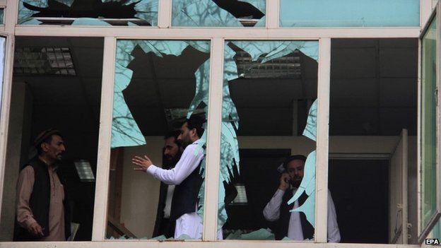 People survey the shattered windows near the scene of a suicide bomb attack outside the New Kabul Bank in Jalalabad, Afghanistan, 18 April 2015