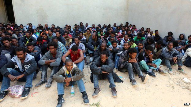 Some of the 340 illegal migrants who were rescued by the Libyan navy off the coast of the western town of Sabratha when their boat began to take on water, sit at a shelter on 12 May 2014