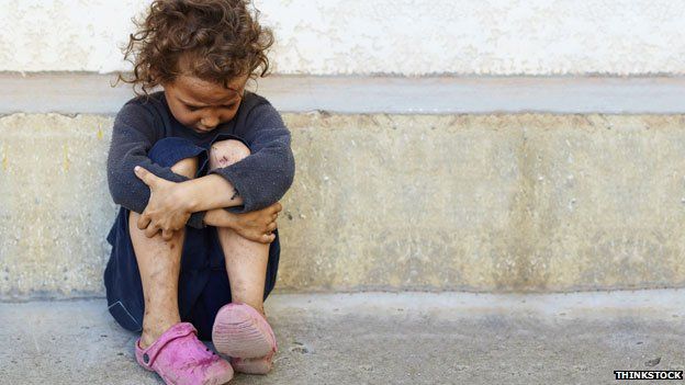 A child sitting on the floor beside a road