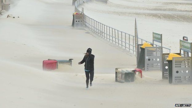 A jogger struggles against sand whipped up by strong winds at Bondi Beach in Sydney on 21 April 2015.