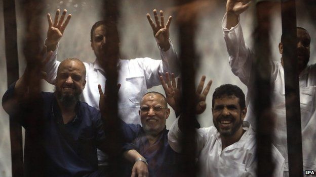Members of the banned Muslim Brotherhood, Essam al-Erian (C) and Mohamed al-Beltagy (L) along other defendants flash the four-finger sign from behind bars during a trial session, in Cairo, Egypt, 21 April 2015.