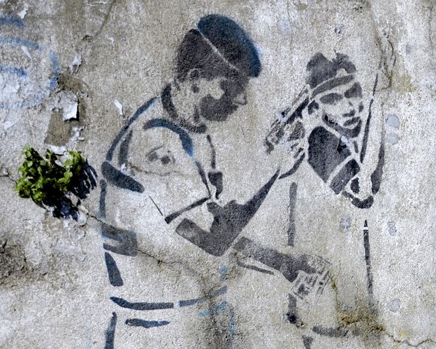 Graffiti of a police officer holding a gun to a man's head