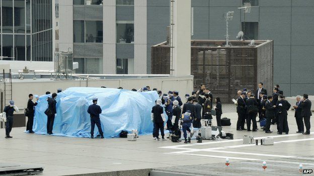 Police surrounding the drone which is covered in blue plastic