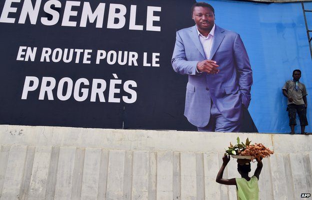 Passers-by walk past a poster of Togolese President Faure Gnassingbe in the capital, Lome.