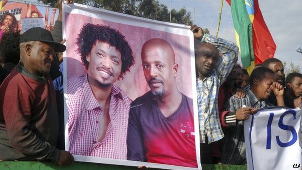 Protesters hold a banner showing two of the people killed by IS in Ethiopia