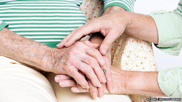 Carer holding the hands of an elderly woman
