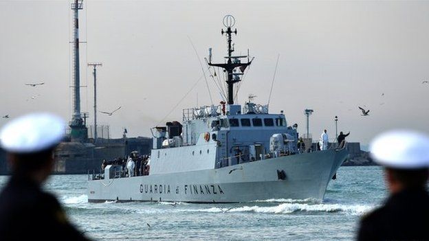 Rescued migrants stand aboard the Italian Guardia di Finanza vessel Denaro upon arrival to the Sicilian harbour of Catania on 23 April 2015.