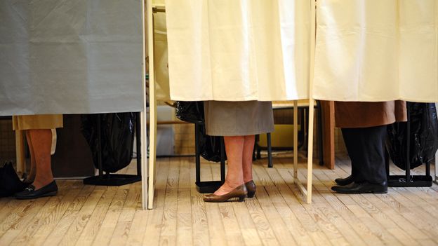 People behind curtained polling booths in France