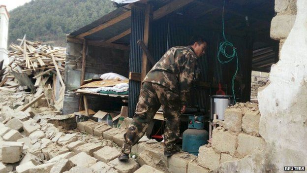 A rescuer looks at a damaged house, after a 7.9 magnitude earthquake hit Nepal, in Xigaze Prefecture, Tibet Autonomous Region, China