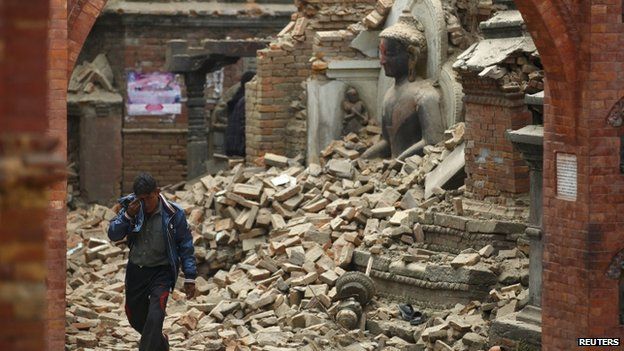 A man cries as he walks on the street while passing by a damaged statue of Lord Buddha in Bhaktapur - 26 April