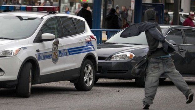 A protester throws a rock at a police car during a demonstration in Baltimore, Maryland, on April 25, 2015, against the death of Freddie Gray while in police custody