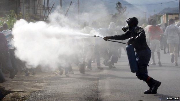 A riot police officer sprays teargas on residents participating in street protests in Burundi