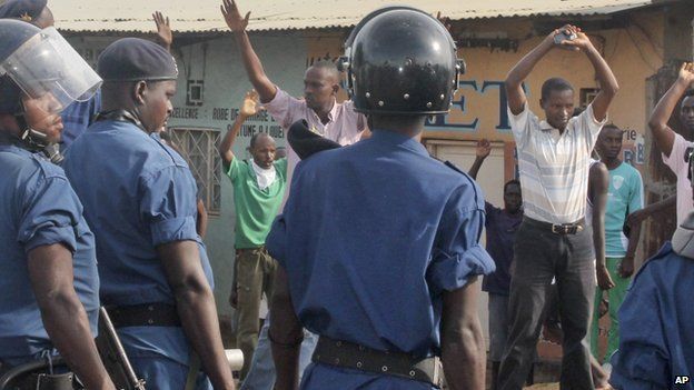 Opposition protesters and others hold their hands in the air when confronted by Burundian riot police in the capital Bujumbura, Burundi Monday, April 27, 2015