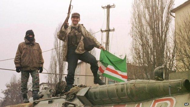 Chechen militants pose for press, as they stay atop APC, with graffiti in graffiti Cyrillic Akbar in Grozny Friday, Dec. 17, 1999.