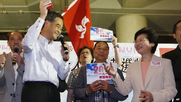 Hong Kong Chief Executive Leung Chun-ying, left, gives a gift to Chief Secretary Carrie Lam, right, during a rally to support the government's political reform proposal in Hong Kong