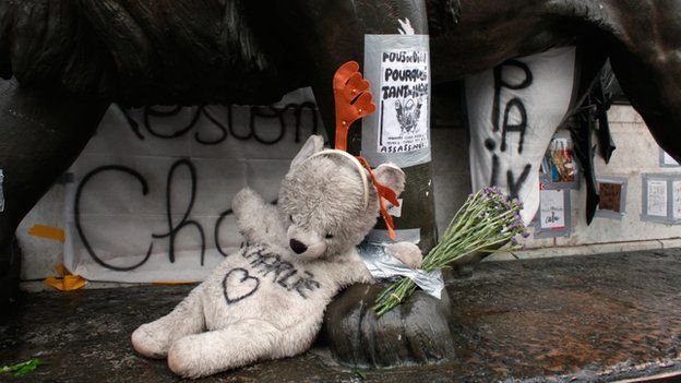 Teddy bear with "Charlie" written on it lays on the statue of the place de la Republique, three months after the terror attack against French satirical newspaper Charlie Hebdo