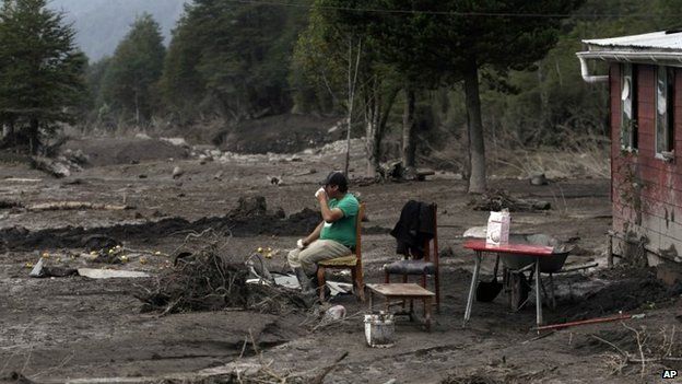 A man waits for evacuation assistance outside his home destroyed by a volcanic mudflow in an area along the Rio Blanco in Puerto Montt on 25 April, 2015.