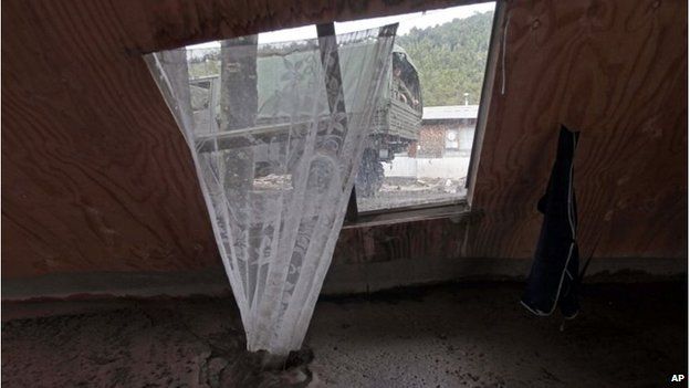 A military truck transporting aid is framed in the the window of a home destroyed by a volcanic mudflow, in an area along the Rio Blanco on 25 April, 2015.